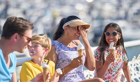 A family sits eating icecreams enjoying their summer holiday in the English Riviera